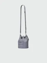 Bolso tipo bucket de cuero color gris con logo "The Bucket Marc Jacobs" estampado en negro. Tiene asa corta de cuerda trenzada y correa larga de cuero ajustable y removible.