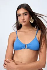 Top de bikini azul con textura fruncida y detalle de aro al frente. Posee breteles finos regulables y un calce cómodo que realza el busto con un toque moderno.