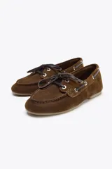 Zapato náutico color marrón de serraje con detalle de pespuntes en el cuerpo y pasados en los laterales. Cierre mediante cordones y suela efecto engomado.