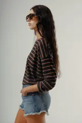 Camiseta de manga larga, corte holgado, con cuello redondo y estampado de rayas horizontales en tonos negro y marrón.