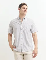 Camisa de manga corta a rayas verticales color blanco y beige con cuello abotonado y bolsillo en el pecho. Cierre con botones color madera.