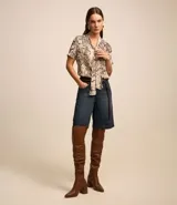 Blusa de chiffon con estampado de serpiente en tonos beige y marrón. Tiene cuello alto con lazo y mangas cortas.