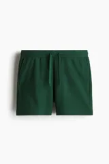 Short deportivo verde oscuro de felpa con cintura elástica ajustable con cordón y bolsillos laterales. Corte regular.