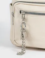 Mochila urbana negra de cuerina con bolsillo frontal con cierre y charm colgante de cadena con dije de corazón y candado. Tiene correas regulables, manija superior, cierre superior, doble bolsillo frontal (uno con charm metálico) y bolsillos laterales.