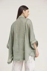 Camisa blanca de lino con corte amplio, cuello camisero y mangas 3/4 con detalle de puntilla en el borde.