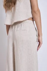 Conjunto de lino color beige, compuesto por un top sin mangas con cuello halter y un pantalón palazzo de tiro alto con cintura elastizada.