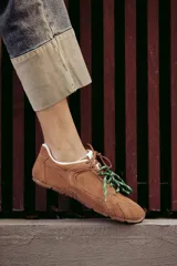 Zapatillas urbanas de cuero color tostado, con cordones verdes y suela de goma.
