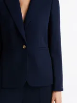 Americana azul marino de crepé con corte slim, solapas con muescas, botonadura sencilla con cierre de botón, dos bolsillos de ojal en la cintura, detalles distintivos de Tommy Hilfiger y logo esmaltado de Tommy Hilfiger en el puño.