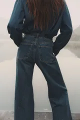 Pantalón de jean azul de corte acampanado, con tiro medio y cinco bolsillos.