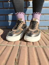 Zapatillas deportivas de cuero color peltre, con suela blanca y diseño moderno.