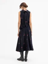 Pollera tipo plato de color negro con estampado de cerezas. Presenta un vuelo caracol irregular, siendo la espalda más larga que el delantero.