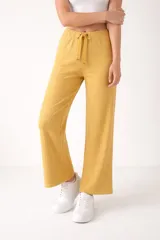 Pantalón de viscosa color amarillo mostaza, de corte ancho y tiro alto, con cintura elástica y cordón ajustable. Presenta un diseño acanalado.