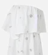 Vestido midi evasé sin mangas, confeccionado en tricolina color blanco, con escote recto con volantes y bordados metalizados de iconos.