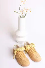 Zapatillas bajas de gamuza celeste con cordones y pañuelos estampados atados a los cordones.