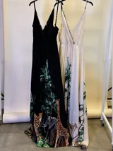 Vestido largo negro con estampado de jungla con palmeras, jirafas y leopardos. Tiene breteles finos, escote en V cruzado y cinturón con apliques brillantes.