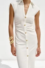 Vestido midi color gris topo, de cuello camisero y escote pico con manga corta. Tiene detalle de drapeado lateral y cierre frontal con botones metálicos.