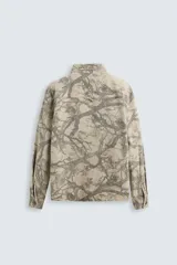 Sobrecamisa color beige con estampado abstracto en tonos grises, de corte relaxed fit, cuello solapa, manga larga con puños abotonados, bolsillos de plastrón en el pecho, efecto lavado y cierre frontal con botones.