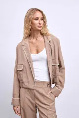 Cazadora color beige con bordados en hilo blanco en cuello, bolsillos y puños.