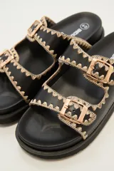 Sandalias negras con doble tira y hebillas doradas.