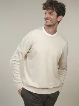 Sweater de punto color beige claro, de corte clásico y cuello redondo.