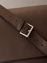 Cartera tipo mensajero con solapa y cierre magnético, confeccionada en piel sintética texturizada (micro pebble). Presenta correa ajustable y múltiples bolsillos interiores.