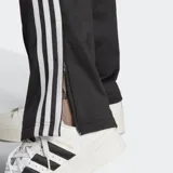 Pantalón deportivo negro de adidas, con 3 Tiras, logotipo bordado y bolsillos con cierre.
