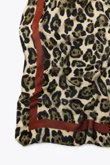Pañuelo cuadrado de modal con estampado animal print de leopardo en tonos beige, marrón y negro. Tiene una banda perimetral marrón.