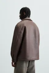 Sobrecamisa marrón de efecto piel con interior de borreguillo a tono, de corte relaxed fit, cuello solapa, manga larga con puños abotonados, bolsillos de plastrón en pecho y laterales, efecto lavado y cierre frontal con botones a presión.