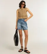 Chaleco color beige de corte sastrero con cierre frontal de cremallera, cuello redondo y bolsillos con solapa.