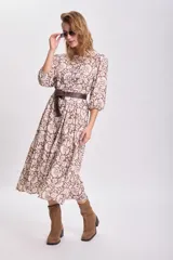 Vestido largo con estampado floral en tonos mostaza, marrón y blanco, con mangas largas abullonadas y falda con paneles. Cinturón marrón con tachas.
