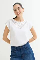 Remera blanca de algodón con cuello redondo y detalle de broderie en el escote.