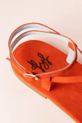 Sandalias planas color naranja de tiras finas, con suela plana y puntera descubierta.