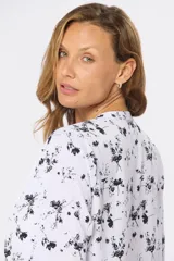 Blusa blanca estampada con hojas en color azul, de manga larga abullonada y cuello redondo.