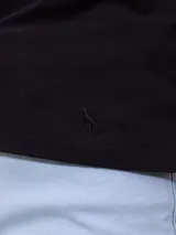 Remera polo blanca de piqué con cuello sin botones y mangas cortas con ribete a rayas rojas y azules. Corte clásico.