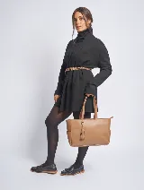 Cartera tote color marrón topo, de cuero sintético, con doble asa corta y cierre superior. Incluye un dije colgante con borla.