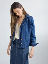 Campera de jean azul con cuello y solapa, corte entallado y largo a la cintura.