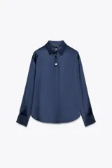 Camisa azul marino de satén con cuello solapa y manga larga. Cierre frontal con botones ocultos por solapa y botones dorados con relieve.