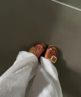 Sandalias de cuero color marrón con hebilla metálica plateada.