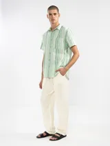 Camisa de manga corta a rayas verticales azules y blancas, con cuello clásico, corte cuadrado y calce relajado. Presenta botones de coco con logo y parche distintivo de Polonio. Confeccionada en Italia con mezcla de lino y algodón.