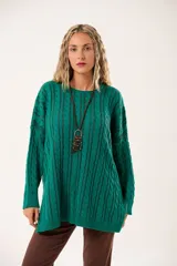 Buzo verde esmeralda tipo poncho oversize, con cuello redondo y mangas largas. Tejido de punto con ochos verticales y fondo vanizado.