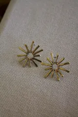 Par de caravanas doradas con forma de sol y centro calado.