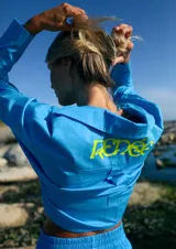 Camisa celeste de manga larga confeccionada en poplín de algodón. Tiene largo a la cintura y canesú estampado en plastisol.