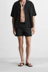Short de baño negro de tejido técnico, con cintura elástica ajustable con cordón, bolsillos laterales y bolsillo trasero.
