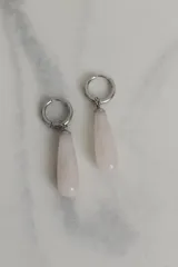 Par de aros colgantes con argolla de acero quirúrgico hipoalergénico y dije en forma de gota de piedra natural color marrón.