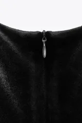 Vestido midi de terciopelo negro, con cuello redondo, sin mangas y detalle drapeado en el frente.