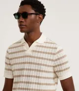 Remera polo de hombre con rayas horizontales color crudo y beige, con textura efecto ganchillo. Corte regular, cuello inglés sin botones y mangas cortas.