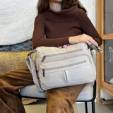 Bandolera de símil cuero color beige, con tres bolsillos frontales con cierre, un bolsillo trasero con cierre y bolsillos internos. Cuenta con una correa larga regulable.