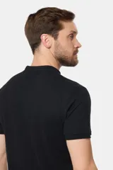 Remera de manga corta color azul grisáceo con cuello mao y tapeta de botones. Los puños de las mangas y el cuello son de color azul marino contrastante. Presenta un pequeño logo bordado en el pecho.