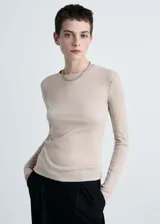 Camiseta color beige de tejido de punto fino con lúrex, cuello redondo y manga larga.