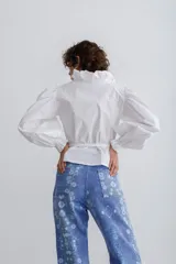 Blusa blanca de mezcla de algodón y poliéster, con lazo en la cintura y cuello alto.